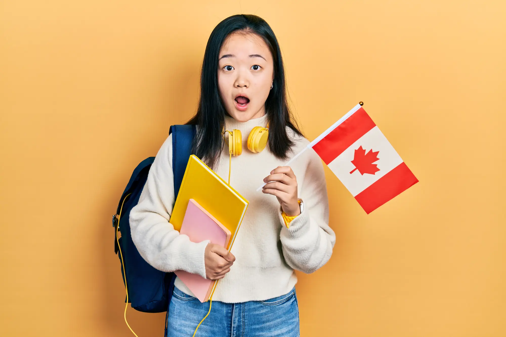 International student holding Canadian flag and study materials, symbolizing Canada study permit process
